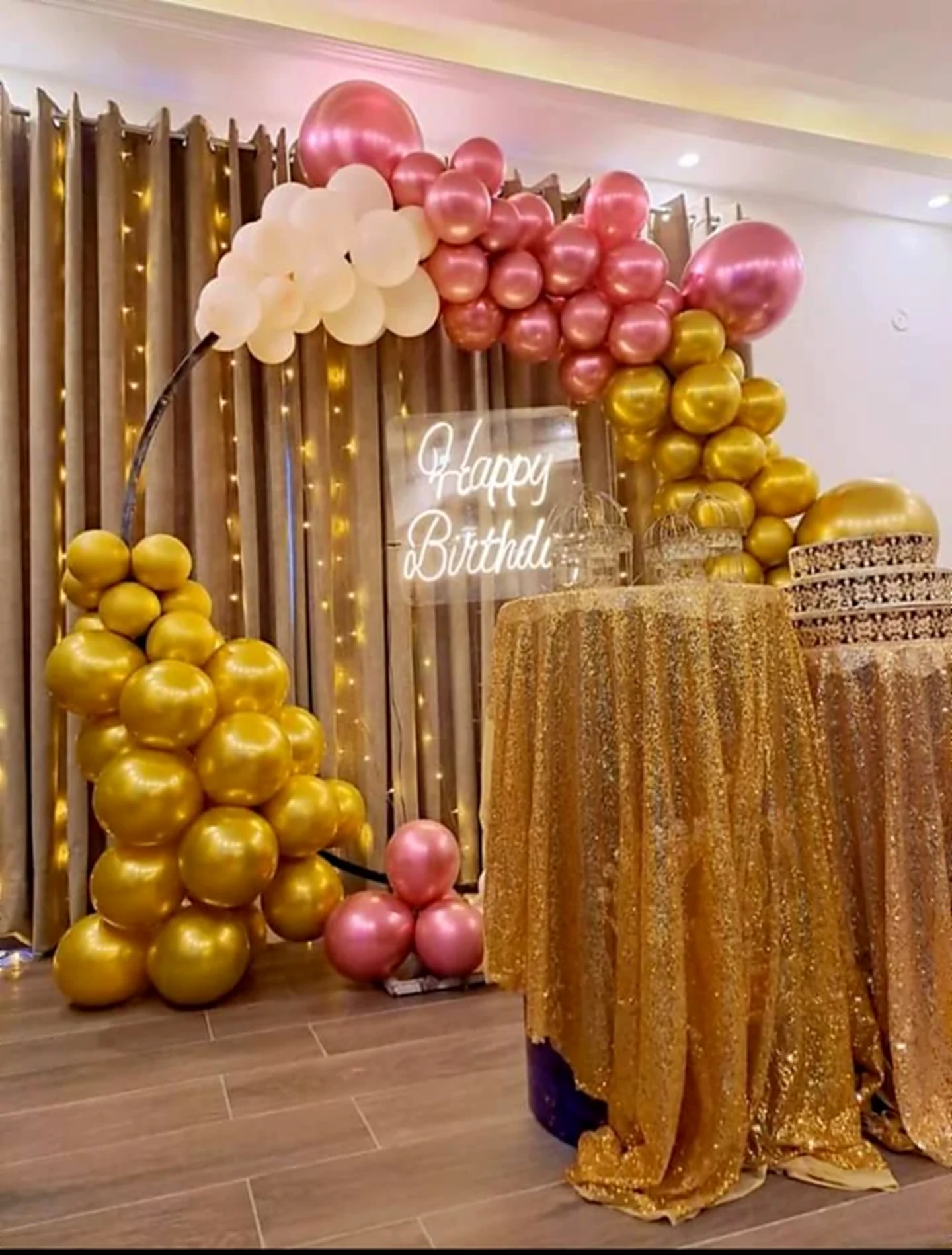 Gold and rose balloon arch with neon happy birthday sign and sequin table
